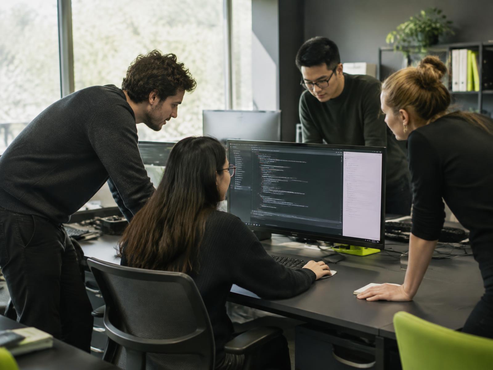 Engineering colleagues collaborating around a software workstation
